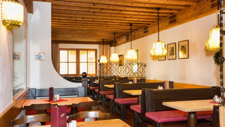 Heuriger, © Wein und Heuriger Ganneshofer Gemütlicher Innenraum eines traditionellen Heurigen mit Holzmöbeln und karierten Sitzpolstern.