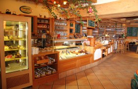 Gausterer, © Gausterer Markus Innenansicht eines gemütlichen Cafés mit Theke und Auslagen.