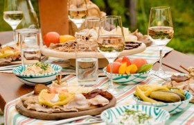 Heurigenjause, © Rita Newman Ein gedeckter Tisch mit Heurigenjause, bestehend aus Aufschnitt, Gemüse und Wein.