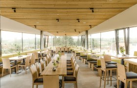 Weingarten.rocks - Buschenschank, © Weingarten.rocks Innenansicht eines modernen Restaurants mit Holzmöbeln und großen Fenstern.