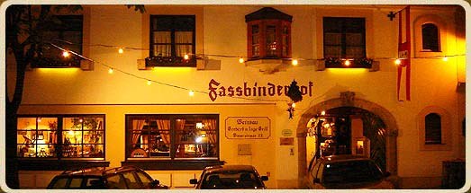 Fassbinderhof, © Fassbinderhof Nachtaufnahme eines Gebäudes mit der Aufschrift 'Fassbinderhof', beleuchtet von Lichterketten.