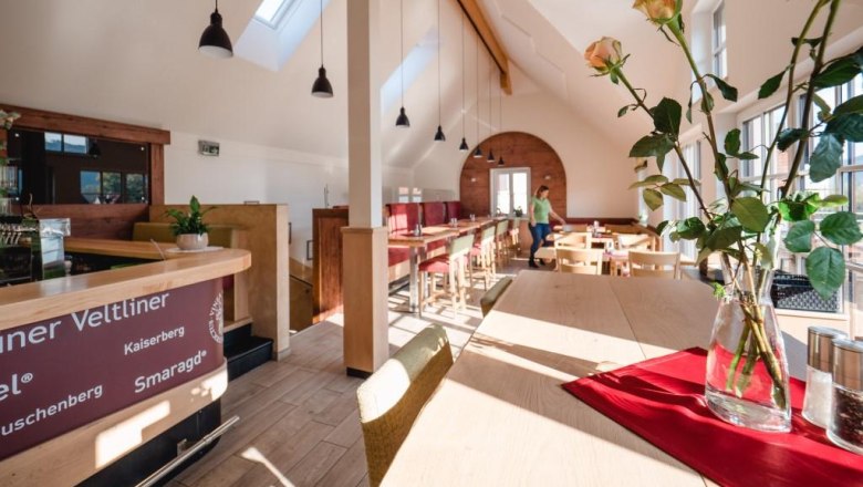 Heuriger Kropf, © Alexander Pfeffel Innenansicht eines modernen Heurigen mit Holzmöbeln und großen Fenstern.