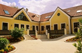 Heurigenbetrieb, © Fam. Groiss Gelbes Gebäude mit roten Ziegeldächern und Garten.