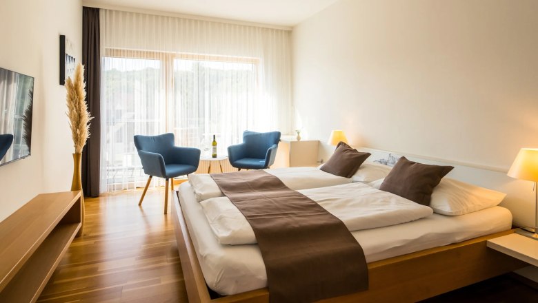 Gästezimmer, © Robert Herbst Modernes Gästezimmer mit Doppelbett, blauen Sesseln und Holzboden.