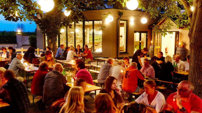 Winzerhaus Kattner, © Winzerhaus Kattner Menschen sitzen abends an Tischen im Freien, umgeben von Bäumen und Lichtern.
