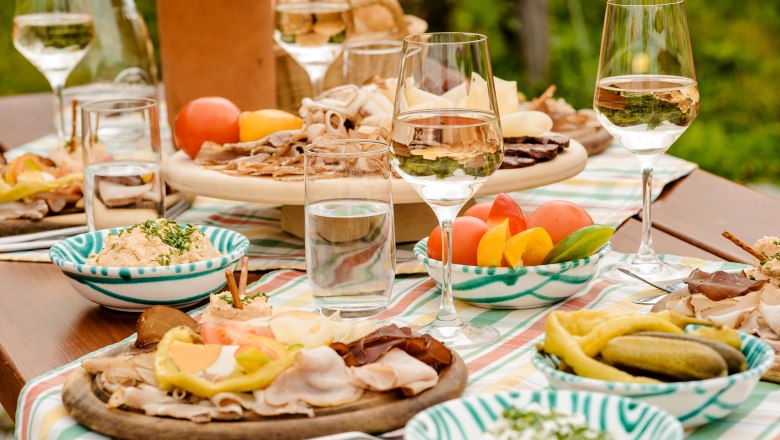 Heurigenjause, © Rita Newman Ein gedeckter Tisch mit Heurigenjause, bestehend aus Aufschnitt, Gemüse und Wein.