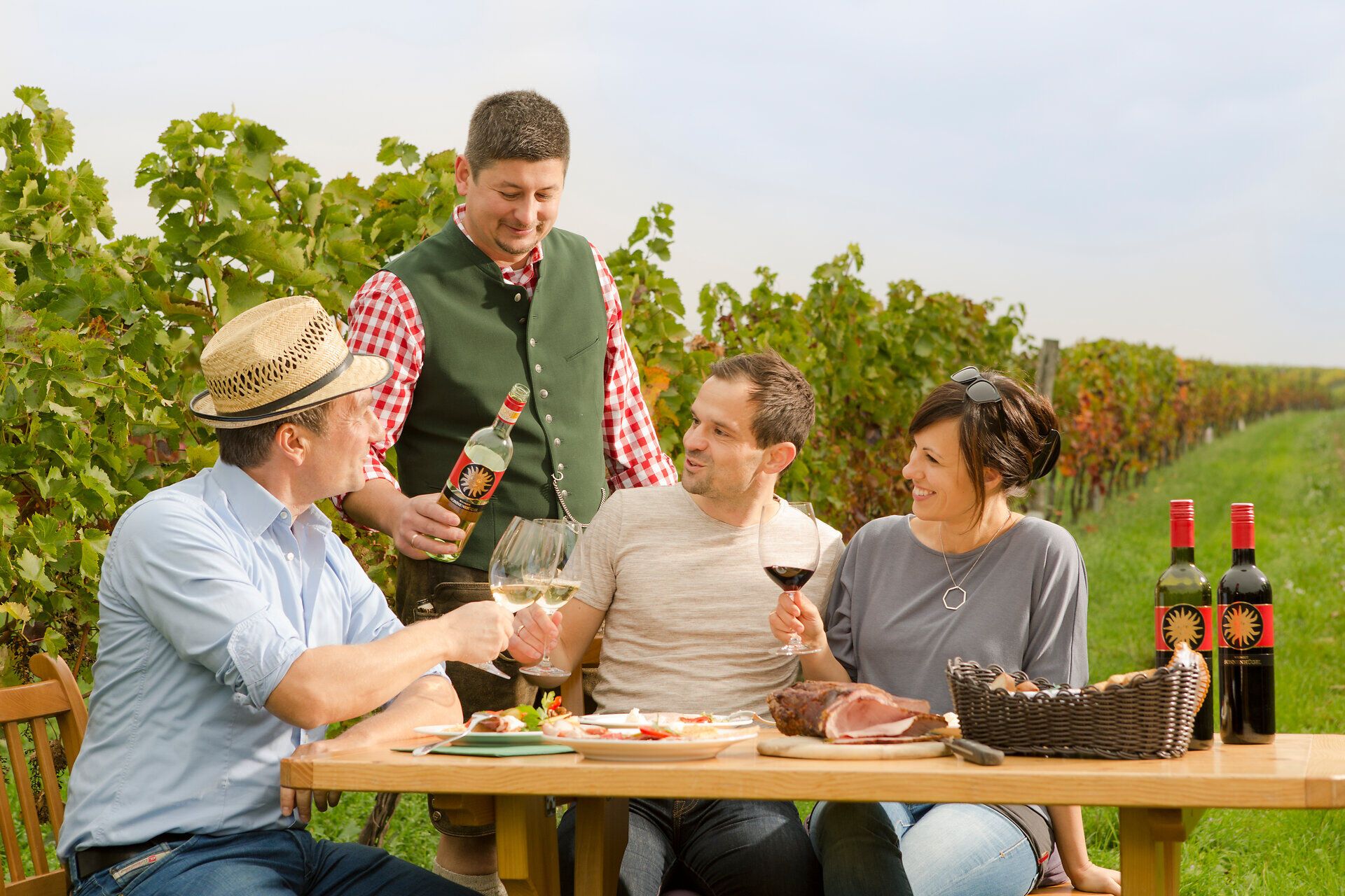 Inmitten der sanften Hügel des Weinviertels genießen Freunde eine fröhliche Weinprobe. Der Tisch ist reich gedeckt mit regionalen Köstlichkeiten, während die Sonne sanft über den Weinreben strahlt. Ein unvergesslicher Moment, der die Seele des Weinherbstes einfängt.