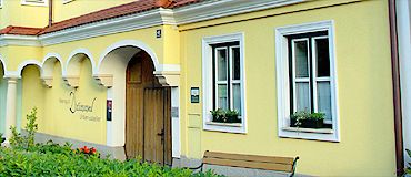 Gelbes Gebäude mit weißen Fensterrahmen und Holztür.