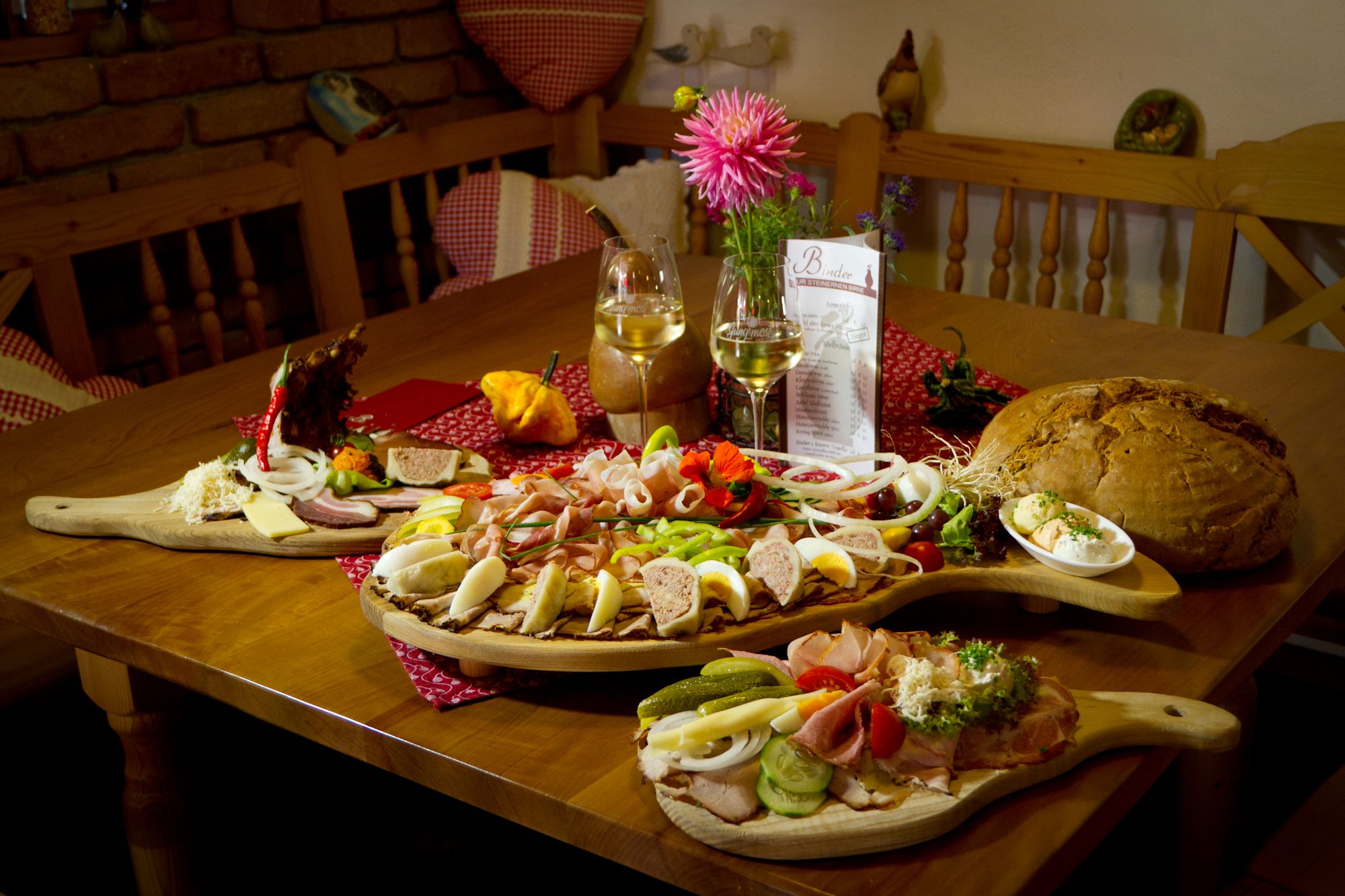 Ein Tisch mit einer Heurigenjause: Aufschnitt, Käse, Brot und Wein.