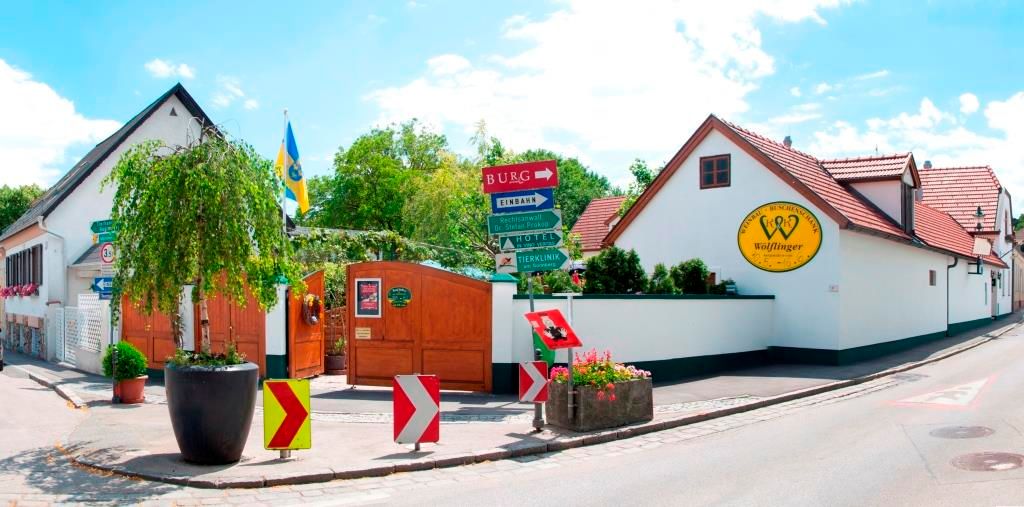 Eingang zum Weingut Wölflinger mit Schildern und Pflanzen.