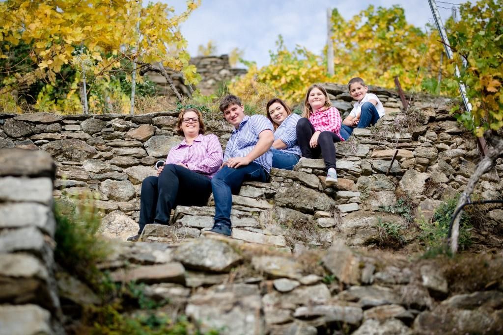 Familie sitzt auf Steintreppe im Weinberg.