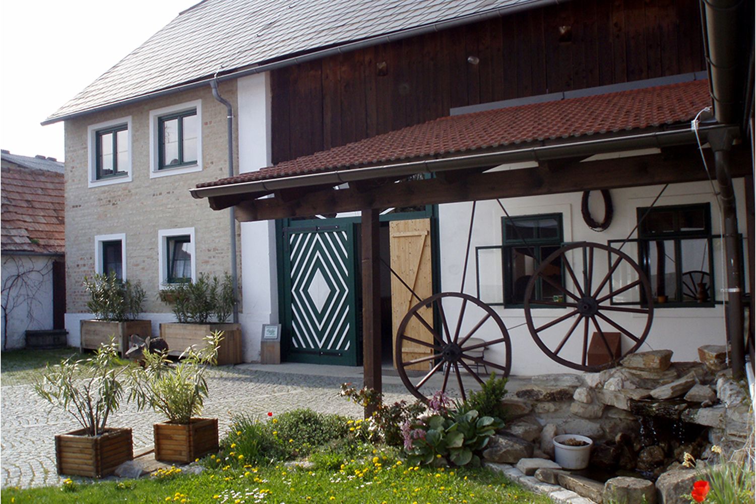 Traditionelles Gebäude mit Holzdach und dekorativen Wagenrädern im Hof.