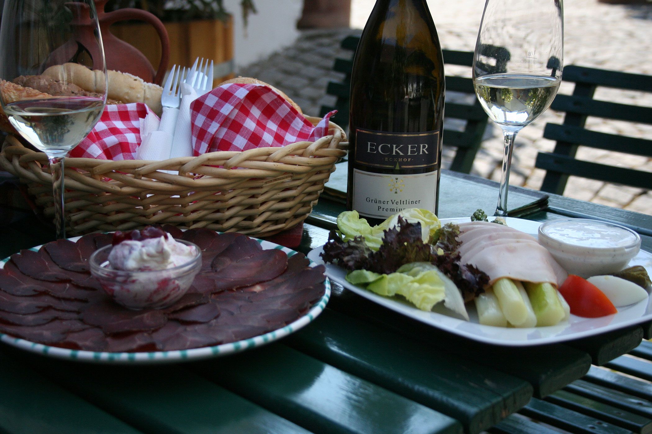 Ein gedeckter Tisch mit Wein, Brot, Aufschnitt und Salat.