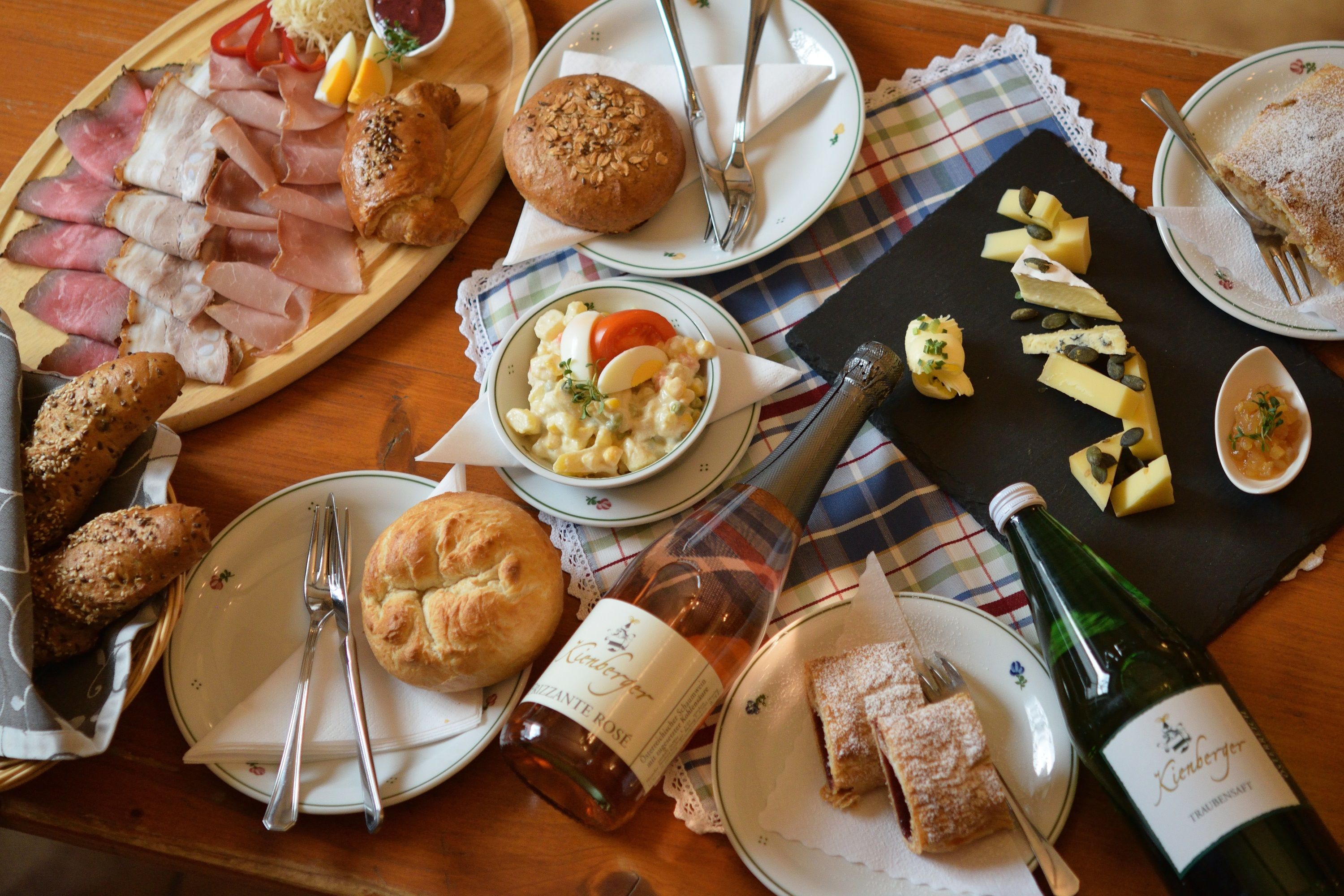 Ein Tisch mit einer Auswahl an Wurst, Käse, Brot, Salat und Getränken.