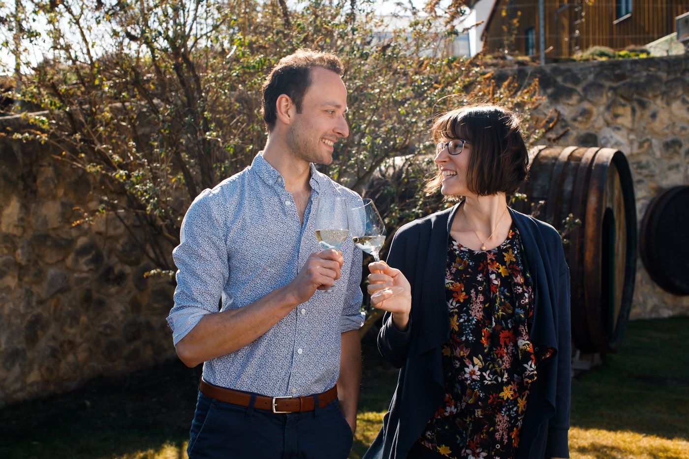 Ein Mann und eine Frau stoßen mit Weingläsern im Freien an.
