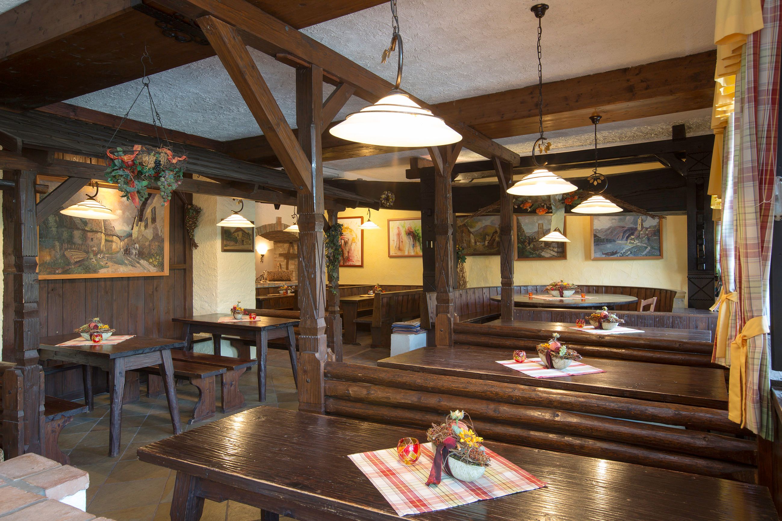 Innenansicht einer traditionellen Heurigenstube mit Holztischen und -bänken, dekoriert mit Tischdecken und Blumenarrangements.