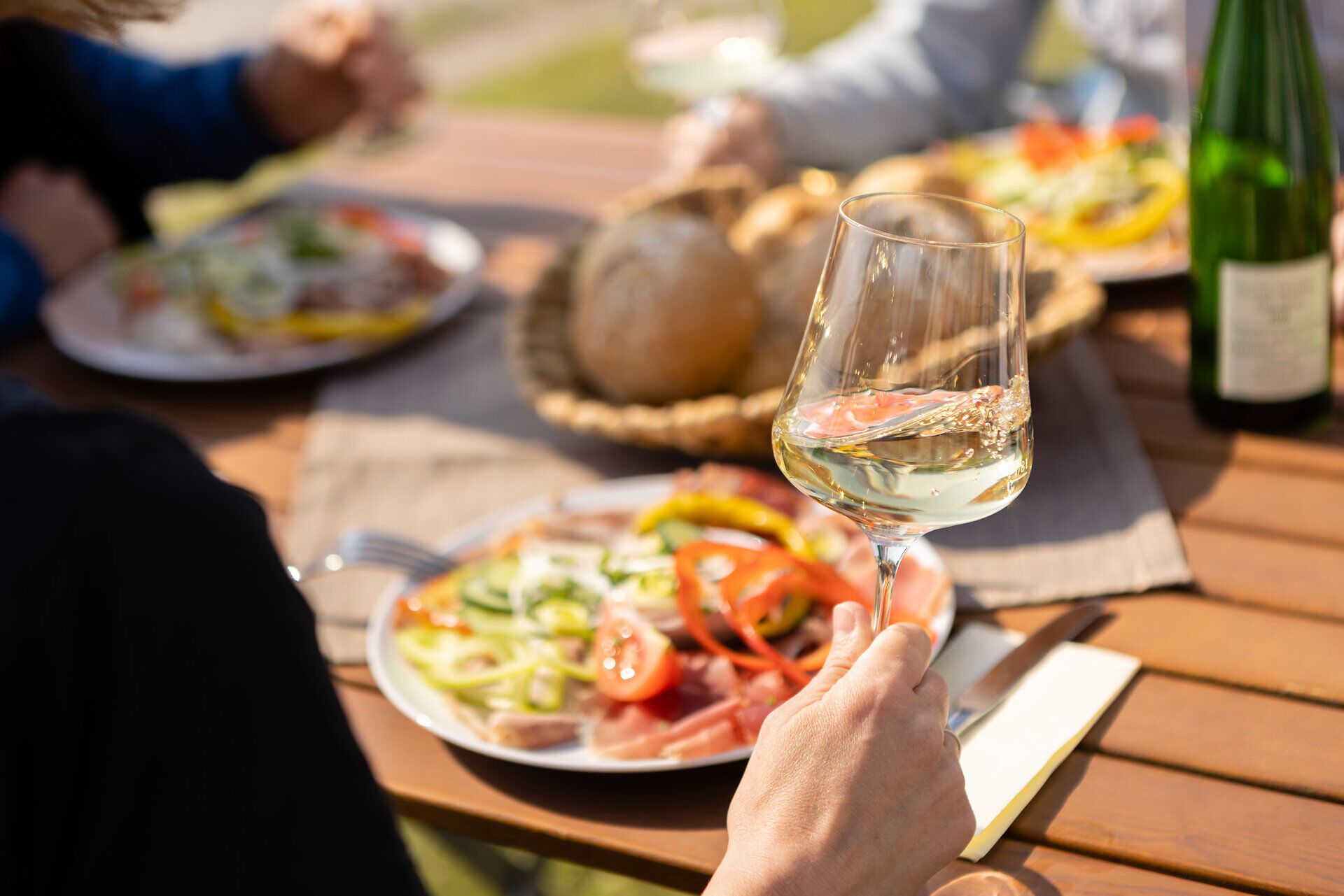 Genießen Sie die köstlichen Aromen des Weins in einer malerischen Umgebung, während Sie sich mit Freunden an einem Tisch im Freien versammeln. Frische, regionale Speisen und ein Glas erlesener Wein schaffen eine einladende Atmosphäre, die zum Verweilen einlädt.