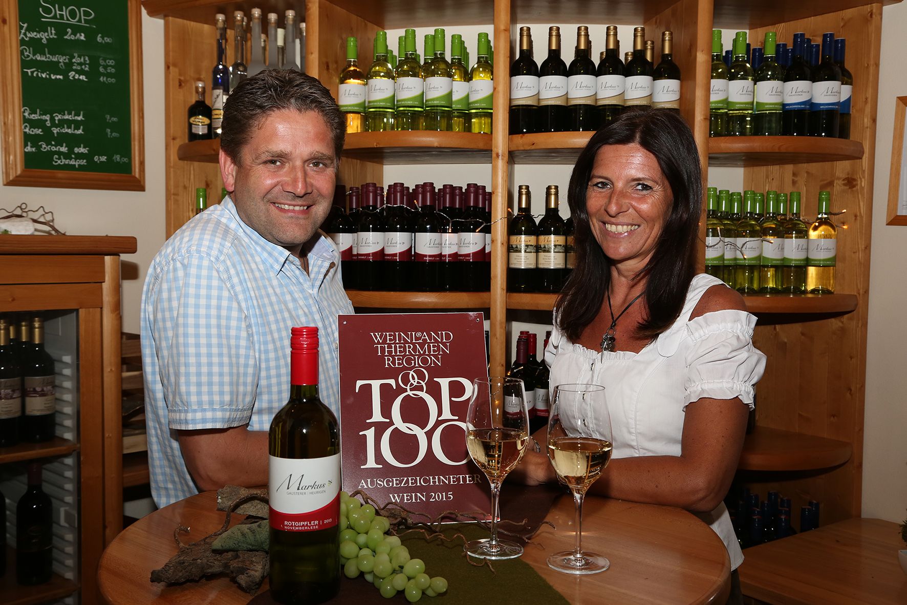 Zwei Personen in einem Weingeschäft mit Weinflaschen im Hintergrund.