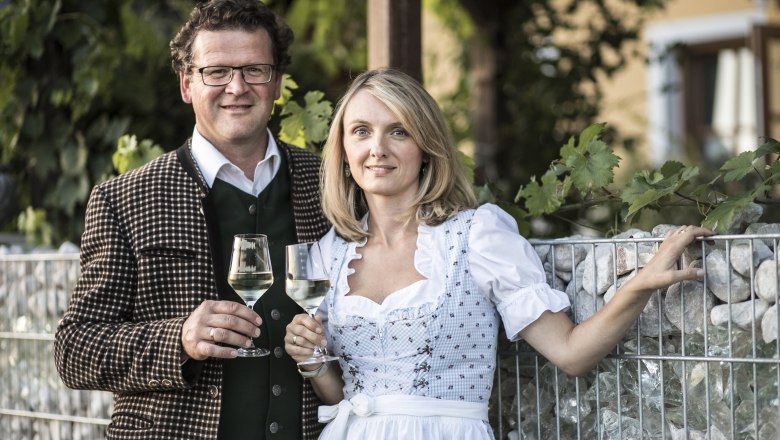 Ein Mann und eine Frau in traditioneller Kleidung halten Weingl&auml;ser in der Hand.