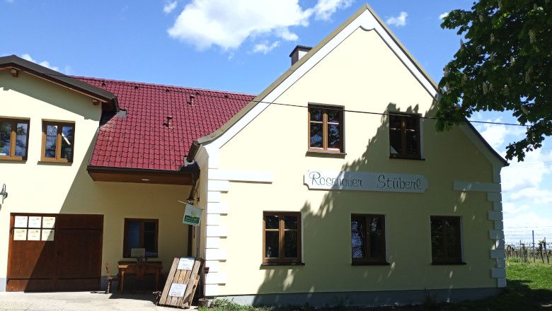 Ein gelbes Gebäude mit rotem Dach und der Aufschrift 'Rosenauer Stüberl'.