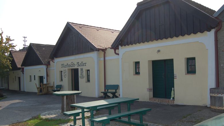 Traditionelle Weinkeller mit Holzbänken und Tischen im Freien.