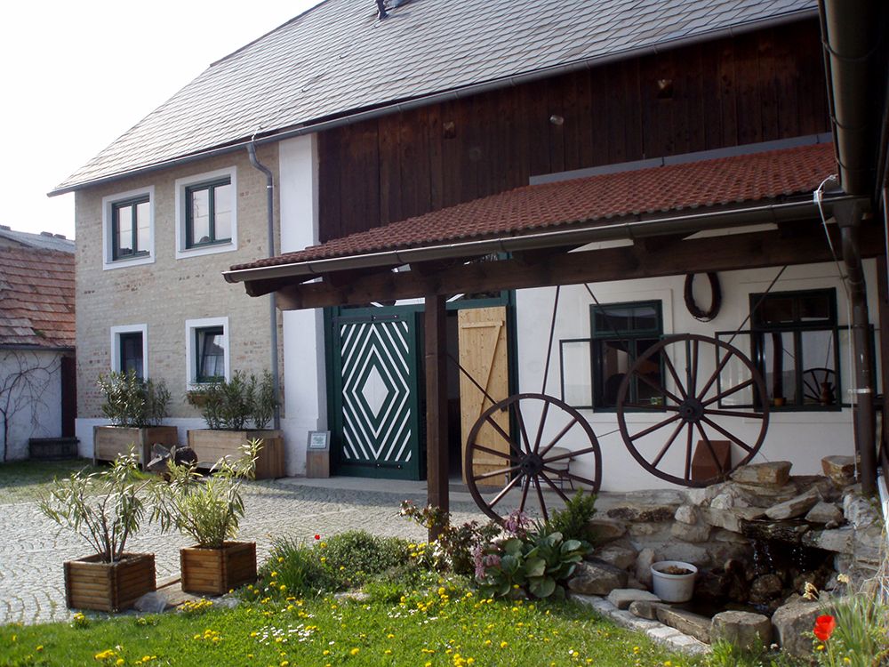 Traditionelles Gebäude mit Holzdach und dekorativen Wagenrädern im Hof.