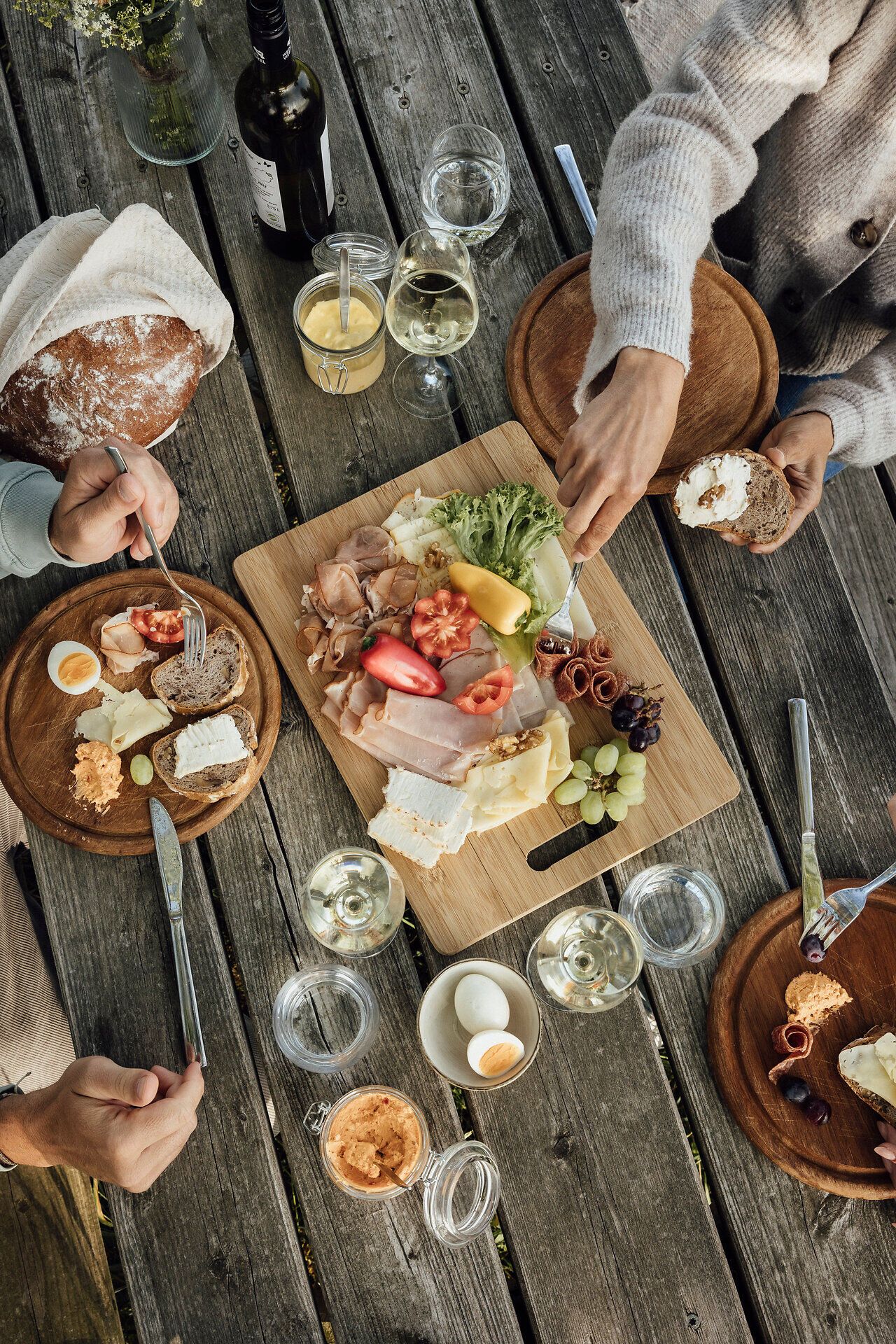 Einladende Tafel mit einer köstlichen Auswahl an regionalen Delikatessen lädt zu einem geselligen Zusammensein ein. Umgeben von der warmen Atmosphäre des Freilufts, genießen die Gäste die frischen Aromen von Käse, Wurst und Obst, während sie den Blick auf die Natur schweifen lassen.
