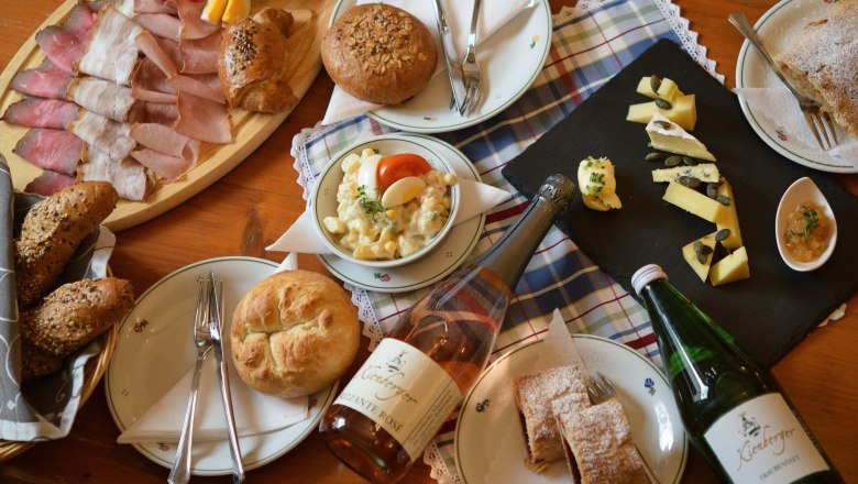 Ein Tisch mit einer Auswahl an Wurst, Käse, Brot, Salat und Getränken.