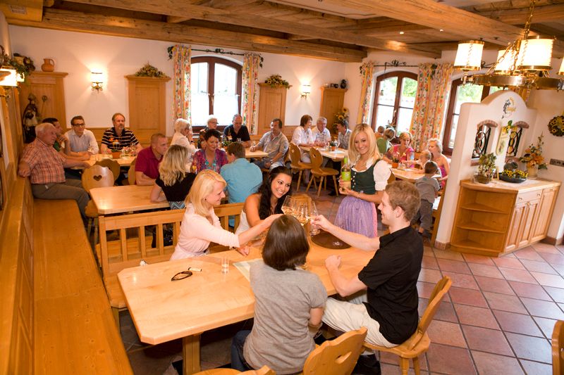 Menschen in traditioneller Gaststube stoßen mit Wein an.