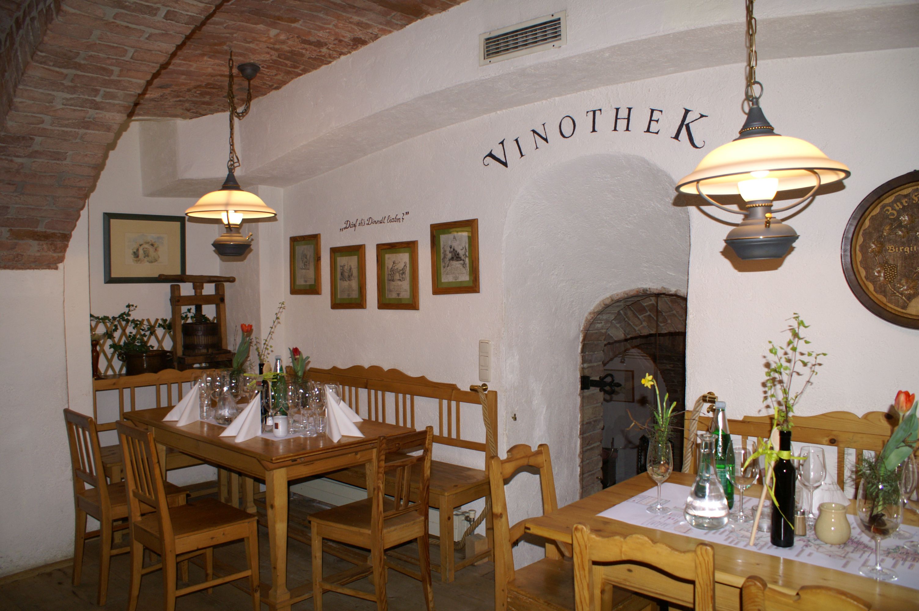 Innenansicht einer gemütlichen Vinothek mit Holzmöbeln und dekorierten Tischen.