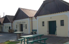 Traditionelle Weinkeller mit Holzb&auml;nken und Tischen im Freien.