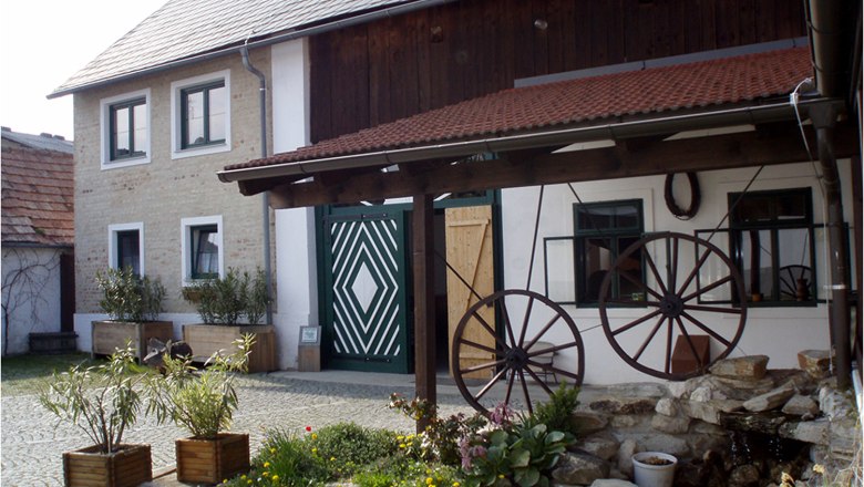 Traditionelles Gebäude mit Holzdach und dekorativen Wagenrädern im Hof.