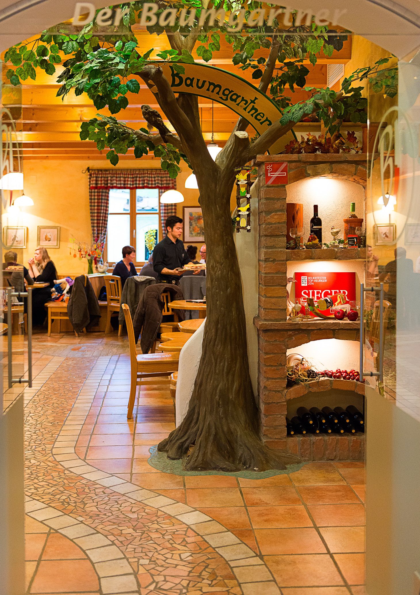 Innenansicht eines Heurigenlokals mit Baumdeko und Weinregal.