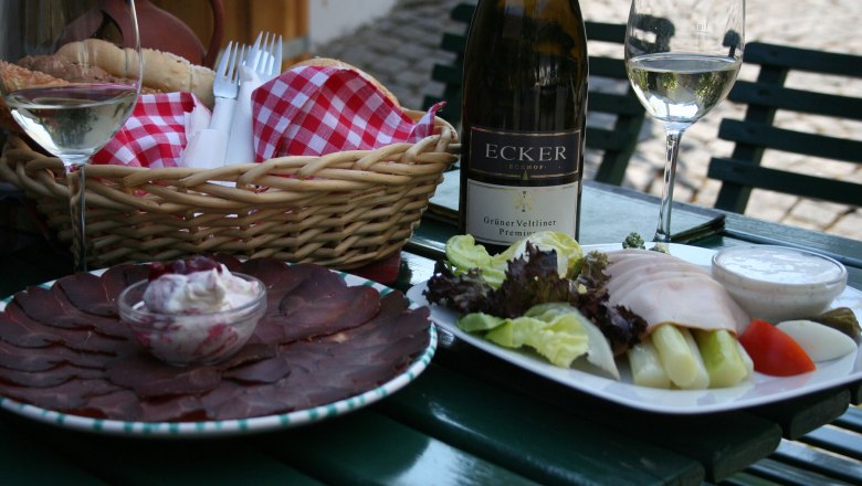 Ein gedeckter Tisch mit Wein, Brot, Aufschnitt und Salat.