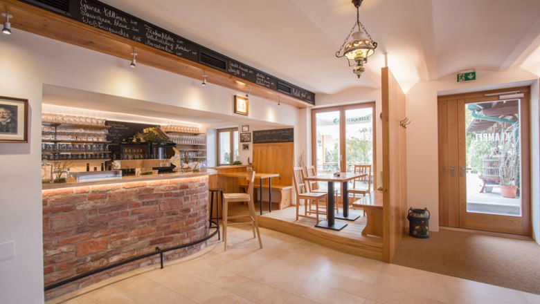 Innenansicht einer gemütlichen Weinbar mit Holzmöbeln und Ziegeltheke.