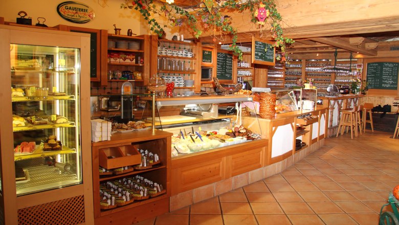 Innenansicht eines gemütlichen Cafés mit Theke und Auslagen.